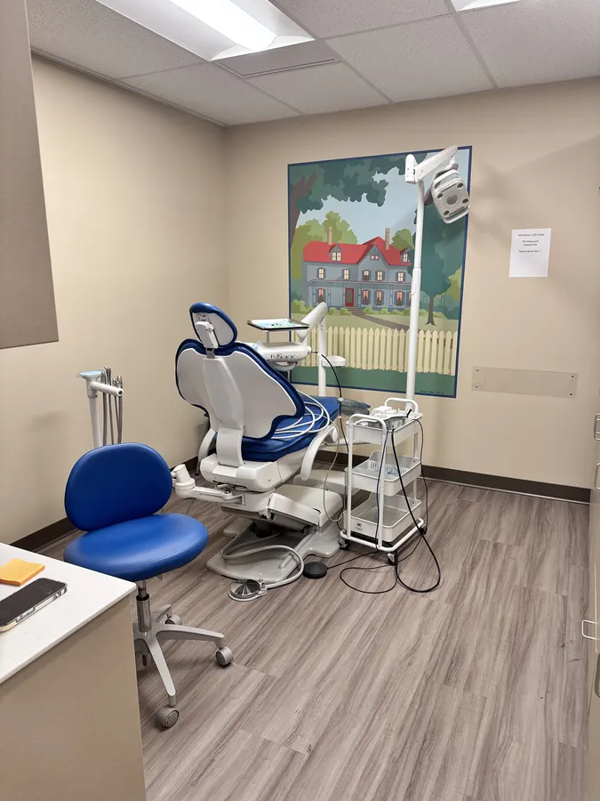A treatment room with a mural of a red house behind a picket fence
